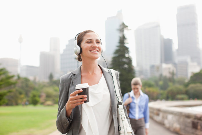 woman walking and listening to podcast to be more productive during her lunch break