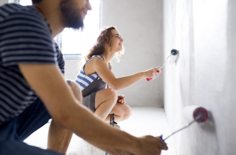 young couple painting walls in their house during a home makeover