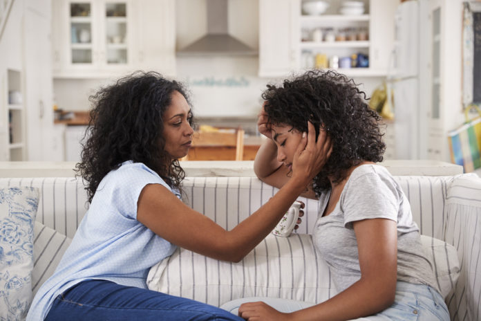 Mother Talking With Unhappy Teenage Daughter to Motivate Teen On Sofa