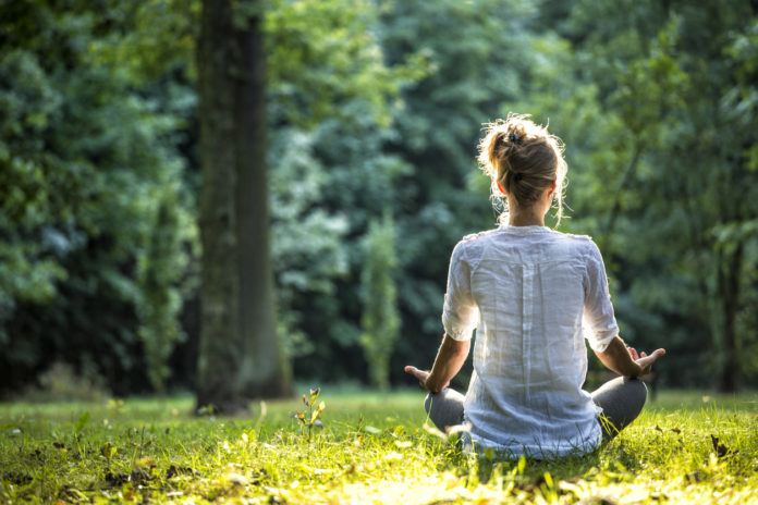 Young, blonde woman meditating in the park