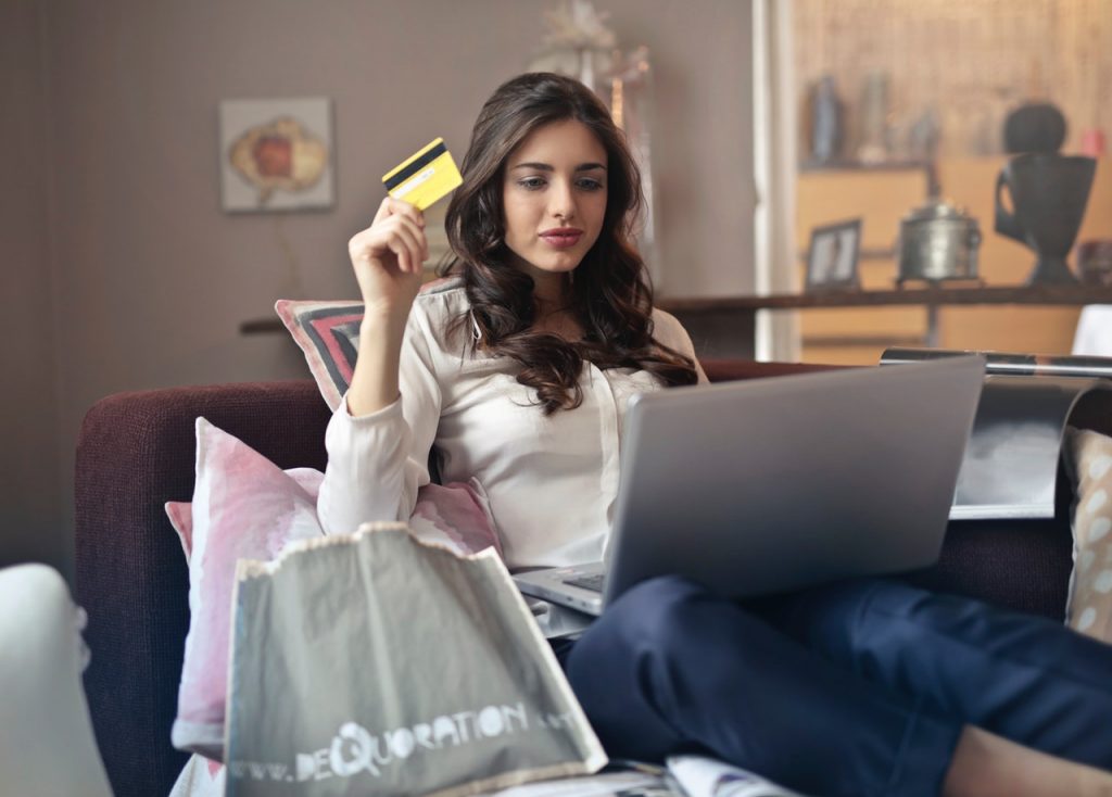 Woman holding credit card working on laptop